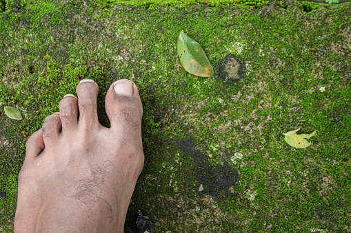 man's left foot steps on the mossy floor