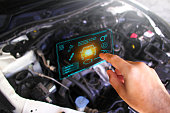 Auto mechanic checking ECU engine system with OBD2 wireless scanning tool and car information showing on screen interface