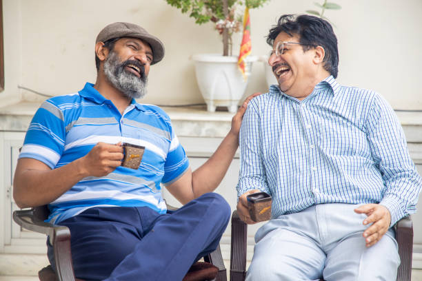 glückliche indische reife freunde, die morgens tee oder kaffee zusammen genießen. häusliches leben oder im ruhestand. - indian culture family senior adult asian ethnicity stock-fotos und bilder