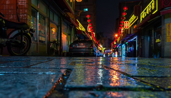 Busan, South Korea - March 19, 2018: Street view with colorful advertising illumination and parked car, Busan Downtown district at night. Selective focus on wet road pavement