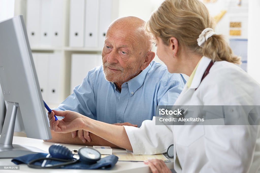 Medical exam doctor talking to her male senior patient at office Advice Stock Photo