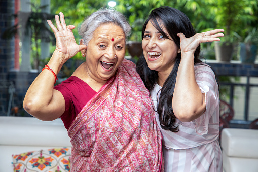 Crazy and cheerful indian mother and daughter make face at camera together. Having fun. Happy Asian family.