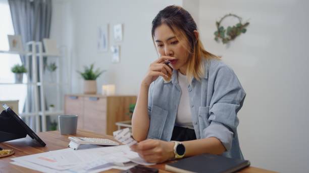 istock Struggle woman having financial problems paychecks paper receipt bill statement ,calculating on calculator monthly expenses debt,planning budgets of monthly personal balance at home. 1541988613