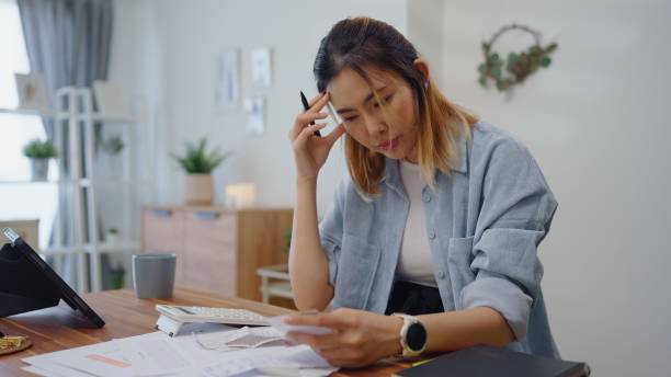 istock Struggle woman having financial problems paychecks paper receipt bill statement ,calculating on calculator monthly expenses debt,planning budgets of monthly personal balance at home. 1541988614