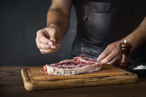 beef marbled steak. Chuck eye roll on the cutting Board.  Organic beef. with butcher hands and meat cleaver at work chop. Space for text.