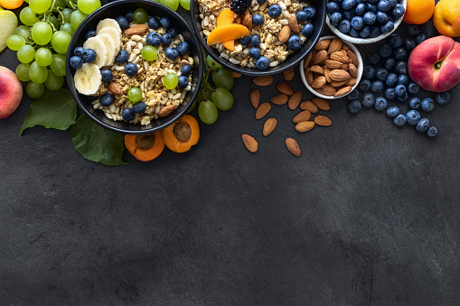 Top view healthy breakfast bowls with ingredients granola fruits greek yogurt and berries on dark background top view with copy space