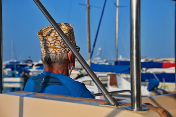 Rear view of senior tourist with Oman hat sitting on the boat