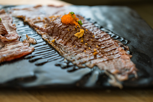 Selective focust to set of grilled Wagyu beef sushi topped with orange ebiko on plate.