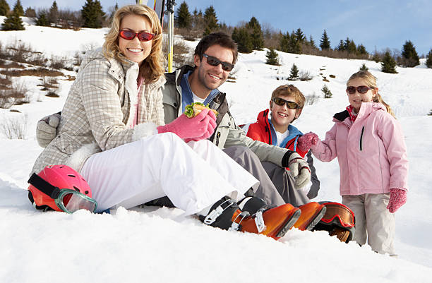 Young family smiling in the snow on ski vacation stock photo