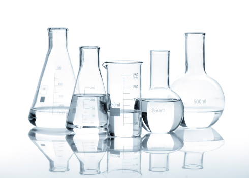 Five glass flasks with a clear liquid, isolated