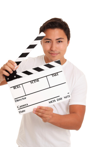 Man holding a film slate, wearing a white t-shirt. White background.