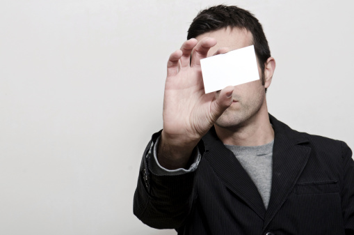 Man Holding Blank business card in Front of Face, Just add your text. in low key