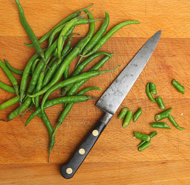 Fresh green chillies being sliced with old chefs knife.