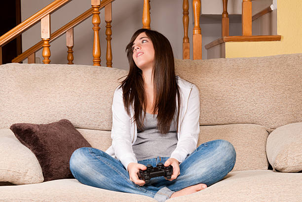 Young female lose playing video-games concentrating on sofa at home stock photo