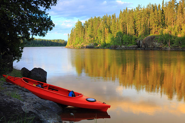 A red and blue canoe at the lake on a lovely day Red canoe sitting on the rocks at the lake in Minnesota, USA boundary waters canoe area stock pictures, royalty-free photos & images