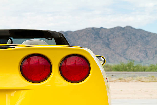 Tail lights of a yellow convertible on a sandy road