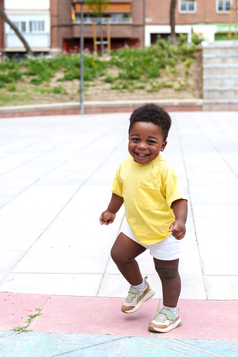 Vibrant portrait: A beaming African 2-year-old races joyfully through a lively city park, spreading happiness