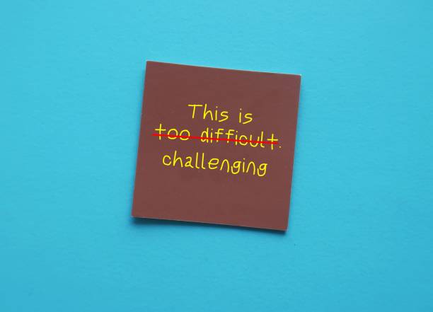 istock Brown card on blue background with handwriting THIS IS TOO DIFFICULT, changed to THIS IS CHALLENGING - concept of turning negative self talk and replaced with positive one - develop growth mindset 1542231862