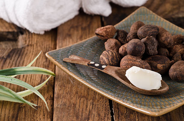 Wooden spoonful of shea butter and I cracked nuts on table stock photo