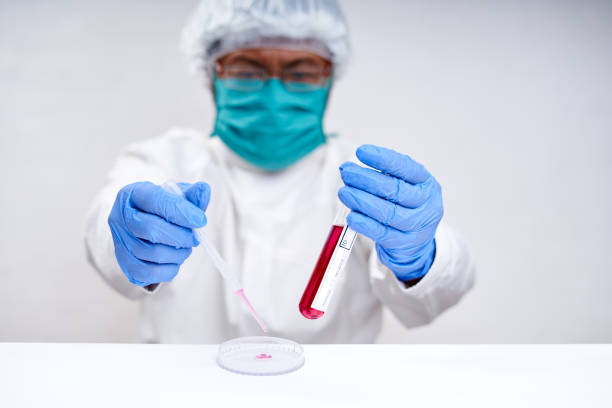 Male scientists in masks and gloves hold Tube With DNA for science tests stock photo