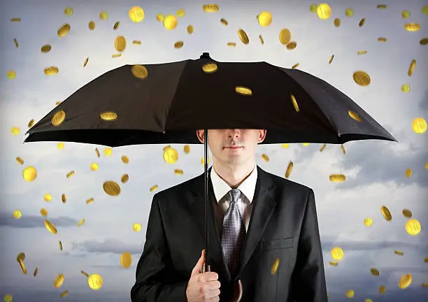 Business man holding an umbrella, money falling from the sky