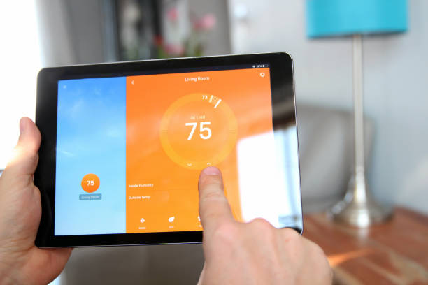 istock Man is Adjusting a  temperature using a tablet with smart home app in modern living room 1542262627