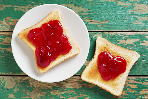 Toasted bread with jam on old green wooden background, top view