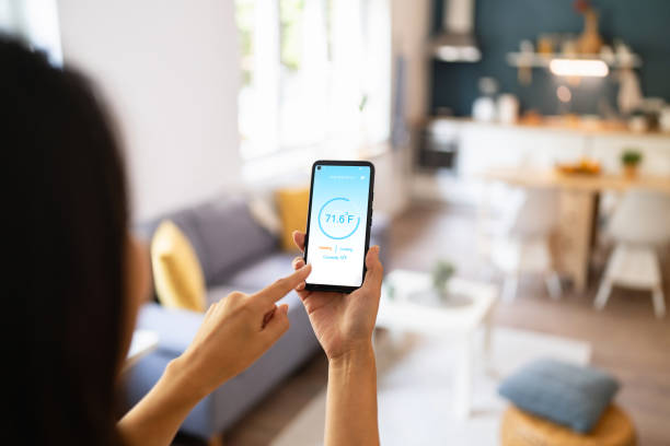 istock Woman holding phone with running smart home application for temperature control 1542270551