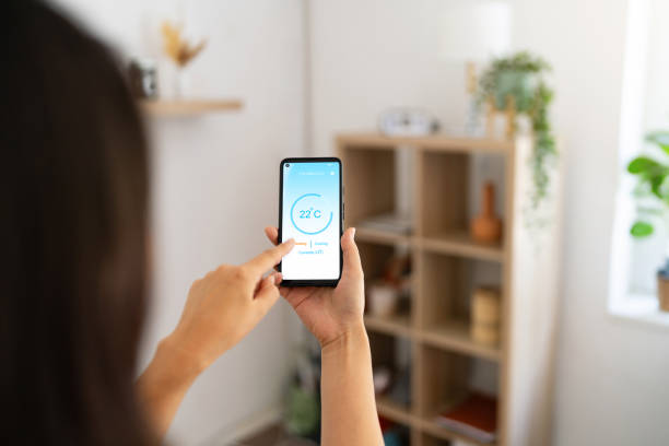 istock Woman holding phone with running smart home application for temperature control 1542270951