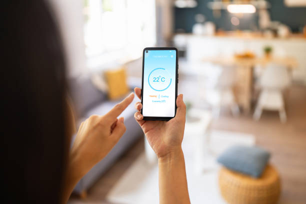 istock Woman holding phone with running smart home application for temperature control 1542271062