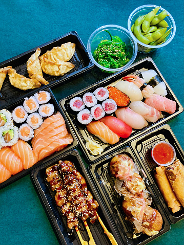 A range of fresh sushi, sashimi and rolls with Japanese dishes including chicken yakitori skewers, takoyaki octopus balls, seaweed salad, deep fried gyoza (dumplings), harumaki (spring rolls) and edamame.