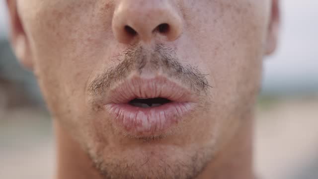 Close-up of young caucasian man with stubble breathing on beach