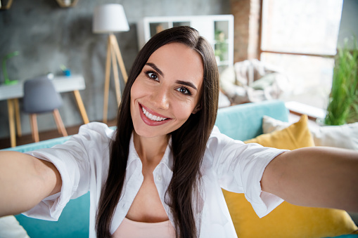Photo of lovely positive person beaming smile make selfie recording video sitting couch free time chilling house indoors.
