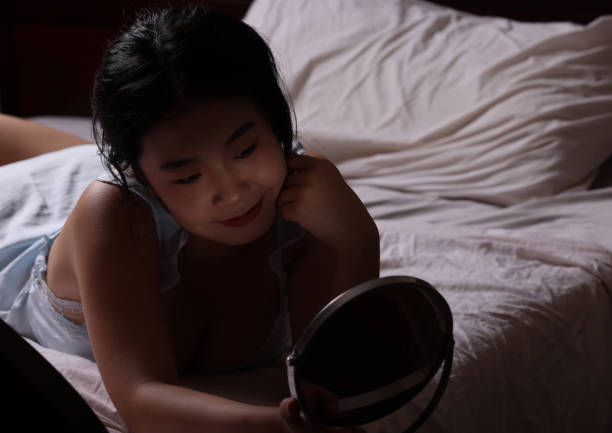 istock Young Chinese student laying in bed doing her make-up 1542320091