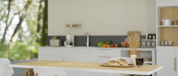 istock Minimal white wooden dining table in a modern minimalist kitchen with kitchen appliances. 1542328636