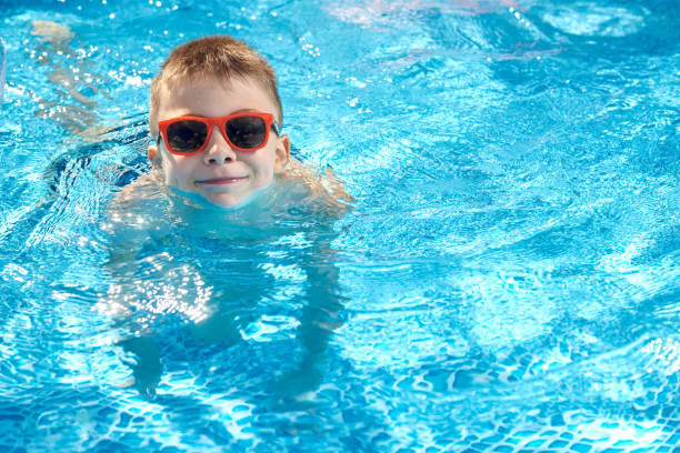 istock The boy swims in the pool and looks at the camera while posing 1542337149