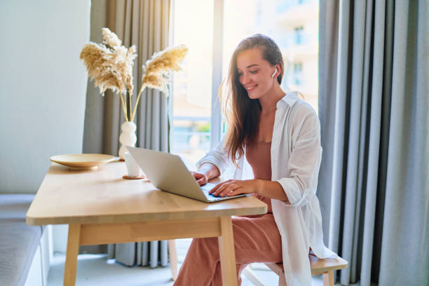 istock Young happy joyful smart modern smiling cute satisfied girl using computer at home interior 1542364100