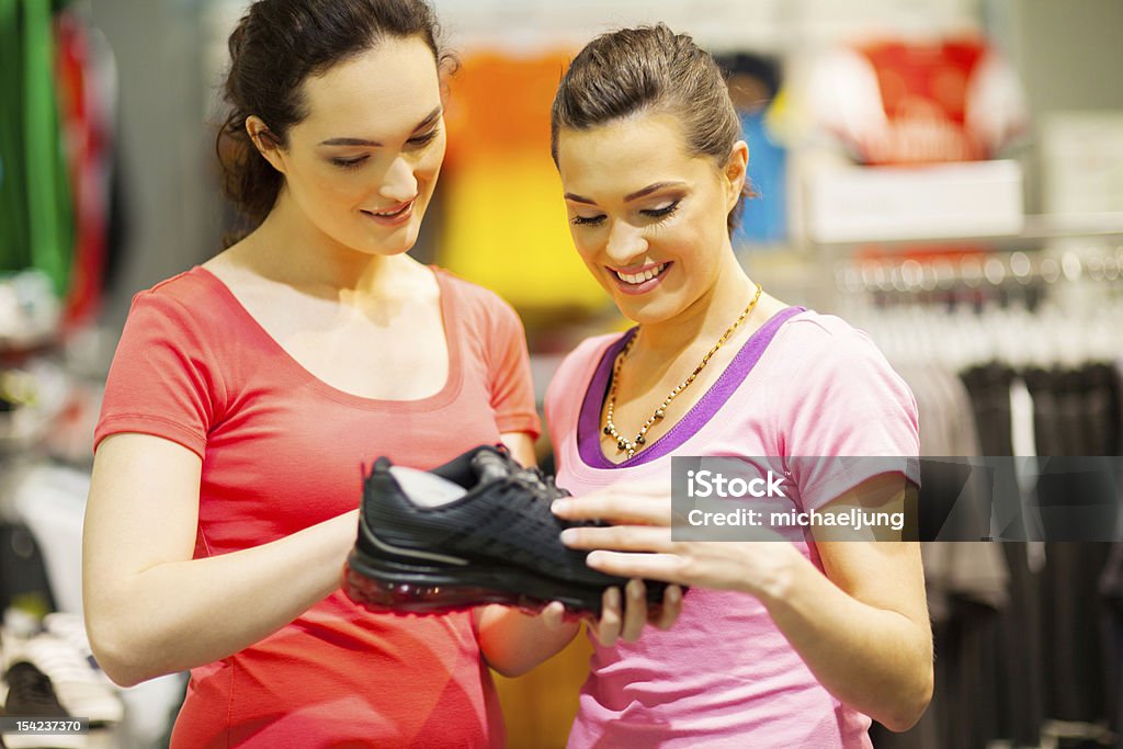 shop assistant helping customer shop assistant helping customer choosing sports shoes Sports Shoe Stock Photo
