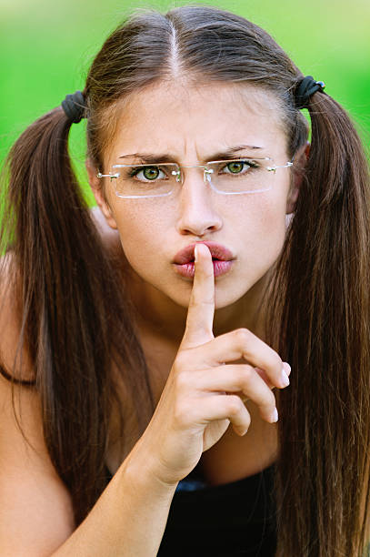 portrait of pretty woman holding finger near her mouth stock photo