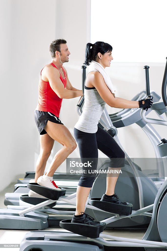 man and woman with elliptical cross trainer at gym man and woman with elliptical cross trainer in sport fitness gym club 20-24 Years Stock Photo