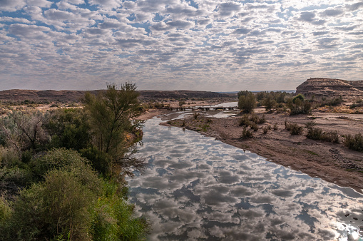 Low hanging clouds are reflected in a water of the Fish river in southern Namibia.
