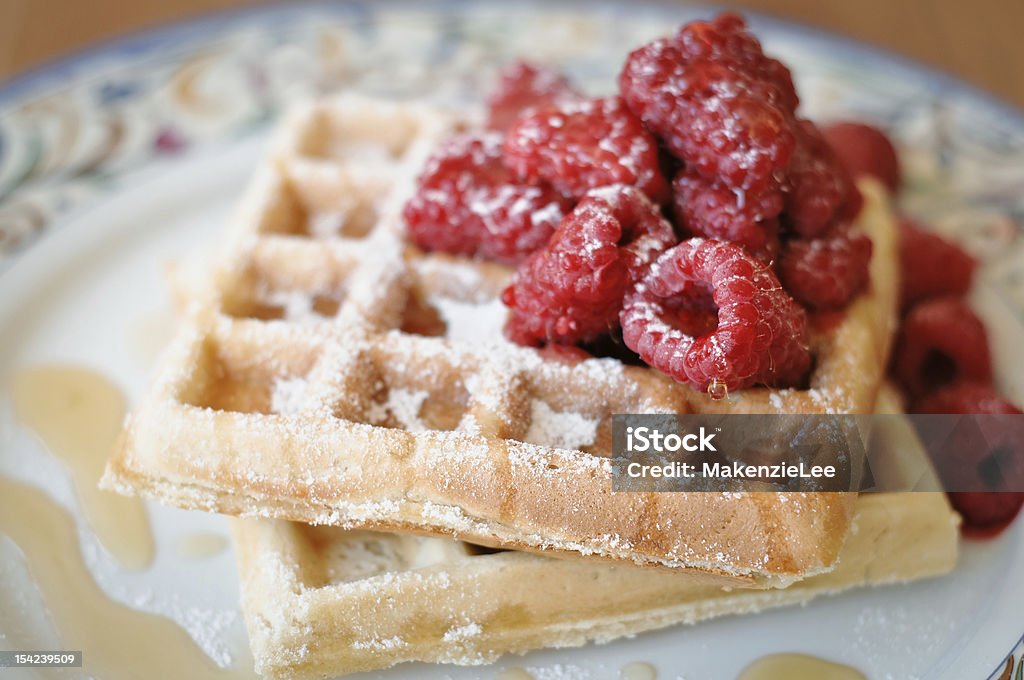 Waffles with Raspberries Two waffles on a colorful plate atopped with fresh raspberries and syrup. Waffle Iron Stock Photo