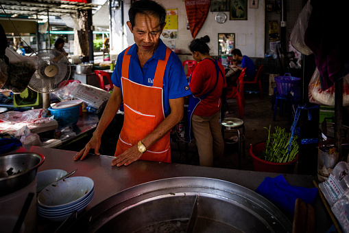 A soup vendor works at their street food stall at a wet market in Bangkok. Daily life in Bangkok, Thailand on July 14, 2023.