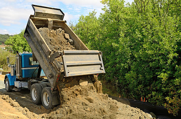 Road Dump A 10 yard dump truck dumps its load of rock and soil on a new road construction project dump truck photos stock pictures, royalty-free photos & images