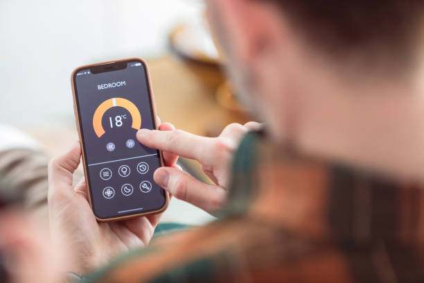 istock Man using mobile phone to control termostat at home 1542449373
