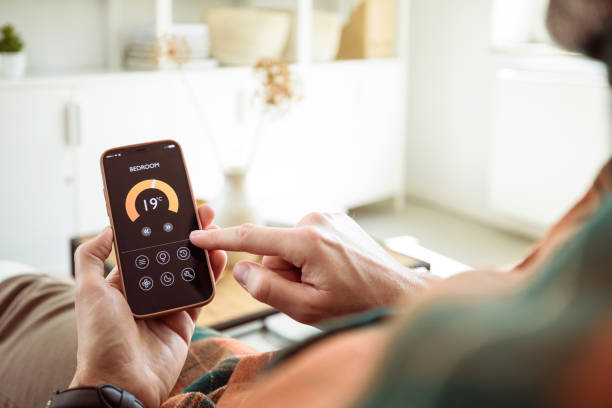 istock Man using mobile phone to control termostat at home 1542450414