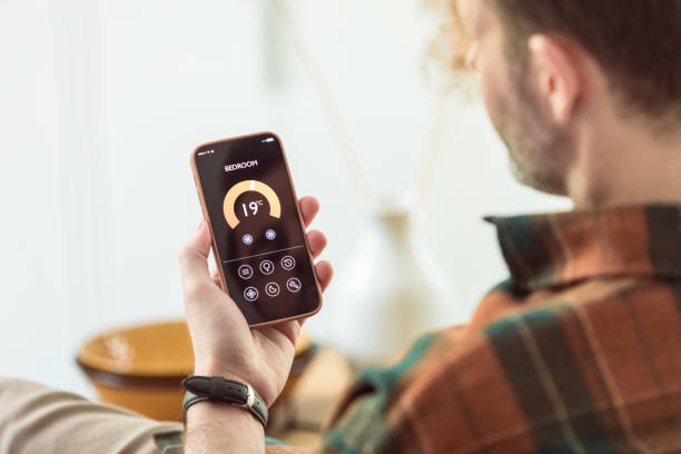 istock Man using mobile phone to control termostat at home 1542450920