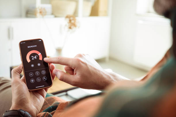 istock Man using mobile phone to control termostat at home 1542451432