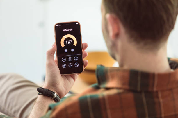 istock Man using mobile phone to control termostat at home 1542451954