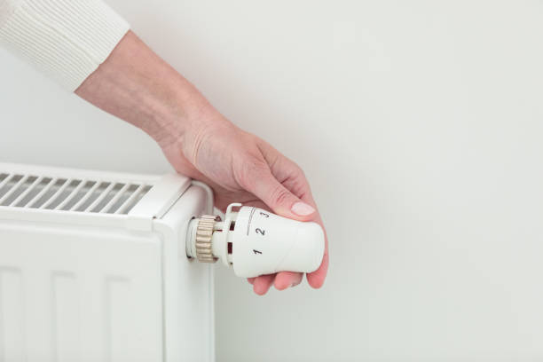 istock Woman adjusting temperature on heating radiator 1542458852